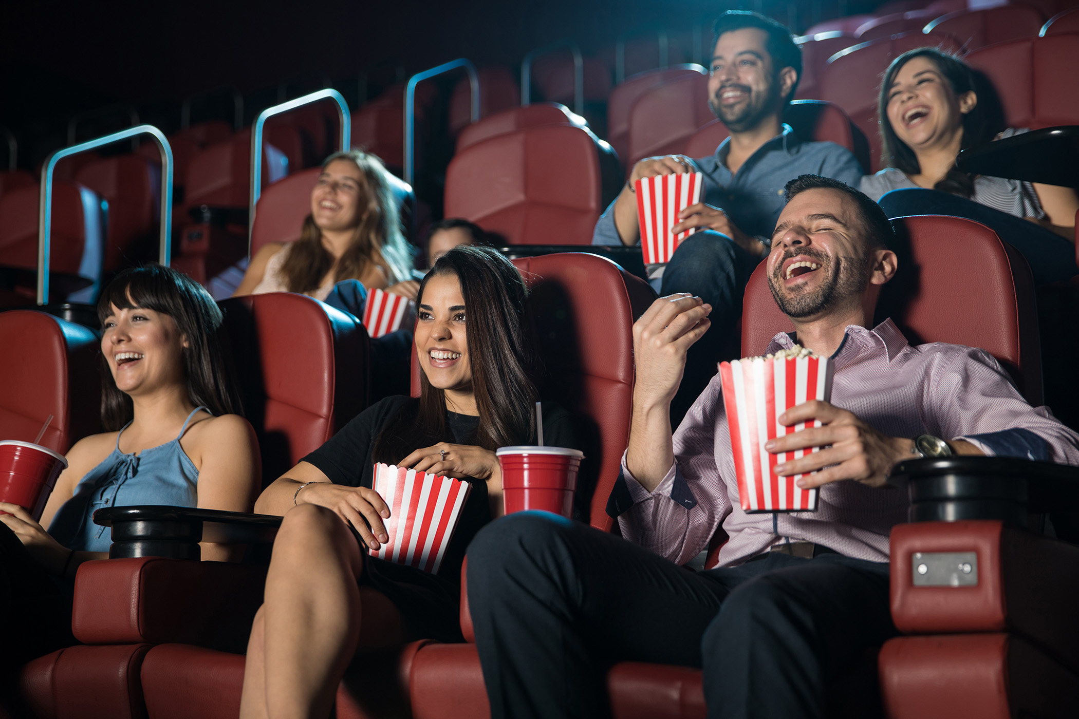 coworkers eating popcorn laughing in a movie theater