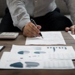 Employee writes on a spreadsheet of forecasting mistakes